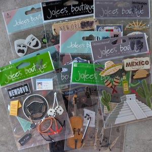 May include: A collection of Jolee's Boutique sticker collages. The stickers feature various themes, including travel, music, and driving. Some stickers have text like "NEWDRVR", "MEXICO", and "Graduation". The stickers are in clear plastic packaging.
