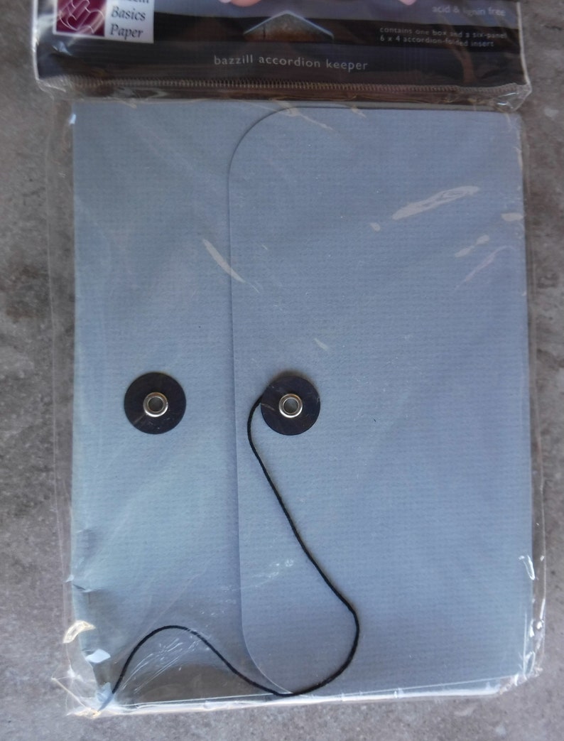 May include: A light blue accordion keeper with black string and two black buttons. The keeper is made by Bazzill Basics Paper and is acid and lignin free. It contains one box and a six-panel 6 x 4 accordion-folded insert.