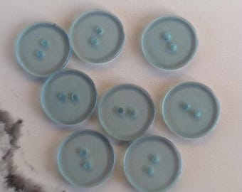 May include: Eight light blue, round buttons with two holes each. The buttons are made of a translucent material, and are arranged in a circular pattern. These buttons are suitable for sewing projects and crafts.