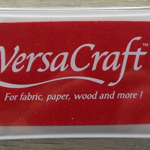 May include: A red ink pad with the text "VersaCraft&trade;" in white lettering. The ink pad is labeled "For fabric, paper, wood and more!"