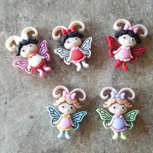 May include: Five colorful plastic fairy figurines with wings and bows. Each fairy has a different colored dress and wings.