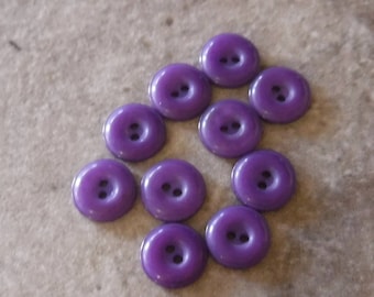 May include: A collection of ten purple plastic buttons with two holes each.