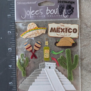 May include: A sticker collage featuring Mexican-themed designs. Includes a sombrero, the word "MEXICO", maracas, a tequila bottle, tacos, cacti, and a pyramid. The package is labeled "Jolee's Boutique Sticker Collage".