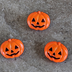 May include: Three orange plastic jack-o'-lantern shaped buttons with black painted details.
