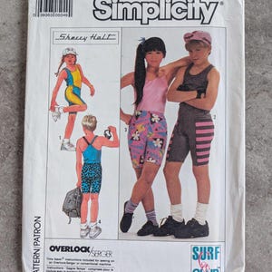 May include: Simplicity sewing pattern featuring children's athletic wear. The pattern includes designs for shorts, tank tops, and a bodysuit. The cover art showcases illustrations of children in the outfits, with the "Surf Club" logo.