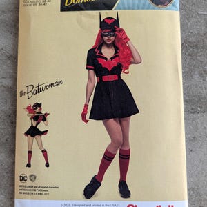 May include: A sewing pattern for a Batwoman costume from DC Comics Bombshells. The pattern features a black dress with red accents, a bat-shaped headpiece, and red gloves. The pattern size is US 6-14.