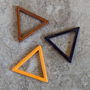 May include: Three triangle-shaped frames in different colors: brown, black, and orange. The frames are made of a thick, glossy material.
