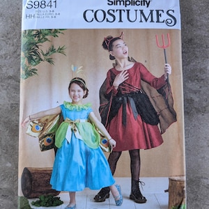 May include: Simplicity Costumes pattern S9841. The package features two children in costumes: one in a blue dress with butterfly wings and the other in a red devil costume with a pitchfork. The package is designed and printed in the USA.