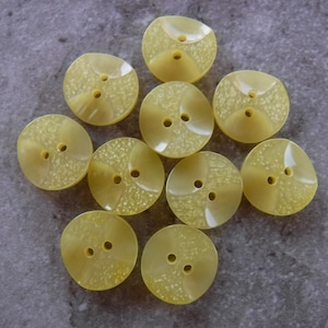 May include: Ten yellow plastic buttons with a textured surface and two holes each.