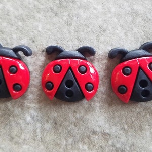 May include: Three red and black ladybug buttons with black spots. The buttons are about 1 inch in diameter.