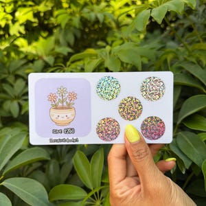 May include: A white ceramic mug with a black handle and the text "But First, Coffee" in a black, handwritten-style font. The mug is on a white surface.