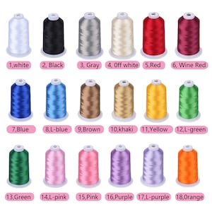 May include: A collection of eighteen spools of thread in various colors, including white, black, gray, red, blue, green, and yellow. Each spool is labeled with a number and color name. The thread is wound on white plastic spools.