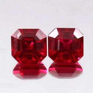 May include: Two vibrant, deep red gemstones with an octagonal step-cut facet pattern. Each stone displays a clear, symmetrical geometric shape with sharp edges and a polished, reflective surface that catches light to create internal brilliance.