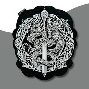 May include: Black round coaster with a white dragon and sword design. The dragon is intertwined with Celtic knot patterns. The coaster has a scalloped edge and the text "WOLF CLAW US" is printed on the top left corner.