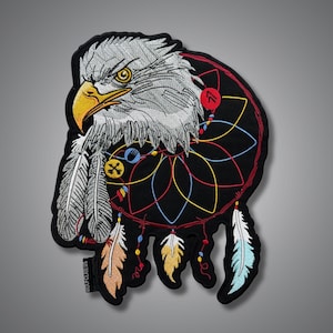 May include: An embroidered patch featuring a detailed bald eagle head with a yellow beak and white feathers, integrated into a black dreamcatcher design with colorful thread accents, hanging feathers, and a small black tag reading WOLFCLAW.US.