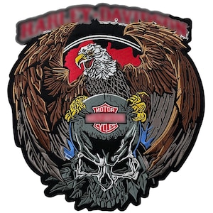 May include: Embroidered patch featuring a detailed eagle with outstretched wings, clutching a shield with the text "MOTOR CYCLES". The design incorporates a skull and the Harley-Davidson logo at the top. The patch has a black border and is suitable for jackets or vests.