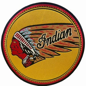 May include: A circular embroidered patch featuring a profile of a person wearing a traditional headdress in red, white, and black against a gold background. The word Indian is stitched in black script across the right side of the design.