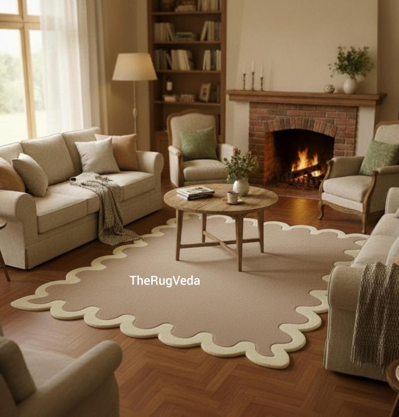 May include: A living room scene featuring a beige rug with a scalloped edge, a wooden coffee table, and a fireplace. The room includes beige sofas, armchairs, and a bookshelf, creating a cozy and inviting atmosphere.