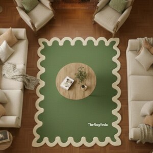 May include: Overhead view of a living room with a green rug with a scalloped edge. A round wooden coffee table sits in the center of the rug. Two cream-colored sofas and two armchairs are arranged around the rug.