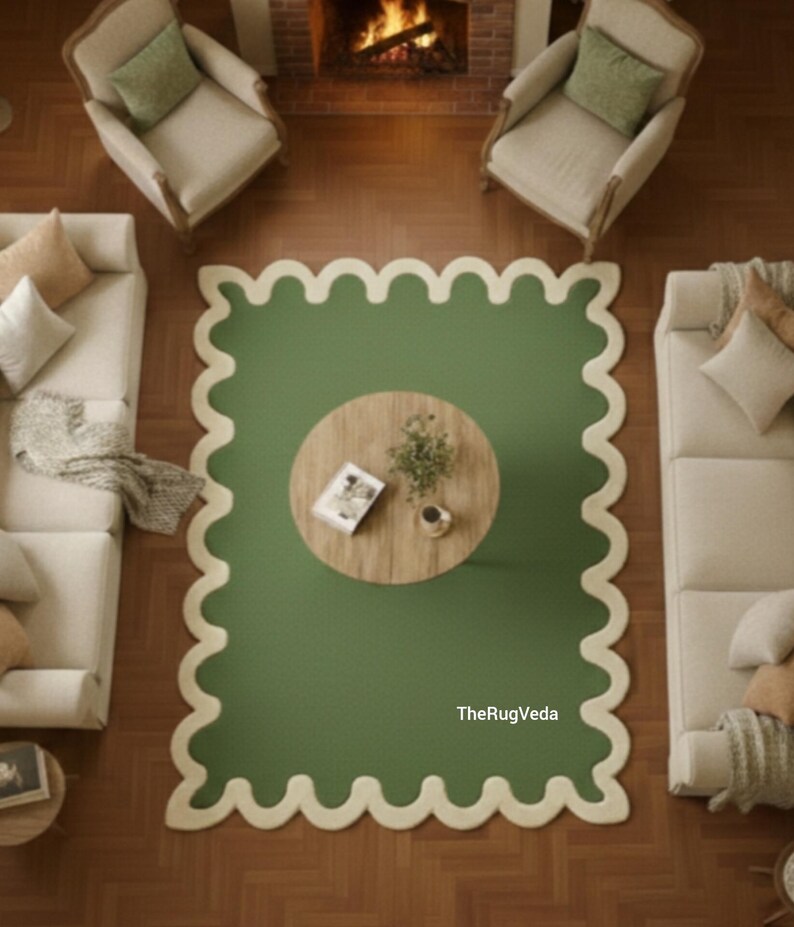 May include: Overhead view of a living room with a green rug with a scalloped edge. A round wooden coffee table sits in the center of the rug. Two cream-colored sofas and two armchairs are arranged around the rug.