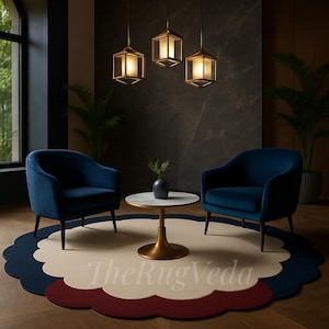May include: A modern living room setup featuring two navy blue armchairs, a small round table, and a patterned rug. The rug has a scalloped edge with cream, navy, and burgundy sections. Three geometric pendant lights hang above the seating area.