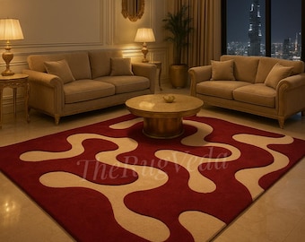 May include: A rectangular area rug featuring a deep red background with a large, flowing, cream-colored abstract pattern. The rug displays the text The Rug Veda in a subtle, light-colored font across the center of the design.
