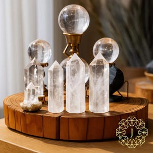 May include: A collection of clear quartz crystal points and spheres. The crystals are arranged on a wooden stand, with some mounted on brass stands. The quartz points are of varying heights, and the spheres are of different sizes. The display showcases natural gemstones.