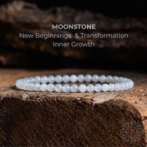 May include: A beaded bracelet made of small, round, translucent moonstone beads with a subtle blue sheen. The text above the bracelet reads: MOONSTONE, New Beginnings & Transformation, Inner Growth. The beads are arranged in a circular shape.