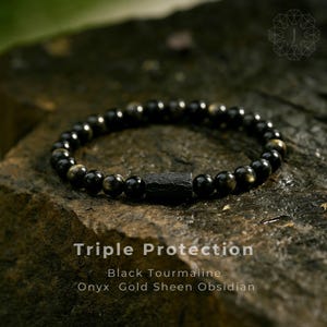 May include: A black beaded bracelet featuring a rectangular black stone. The bracelet is composed of black tourmaline, onyx, and gold sheen obsidian. The text "Triple Protection" is visible below the bracelet.
