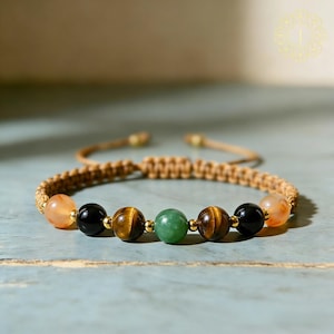 May include: Beaded bracelet featuring a macrame cord and a series of colorful gemstone beads. The bracelet includes orange, black, tiger's eye, and green beads. The adjustable cord is a light brown color.