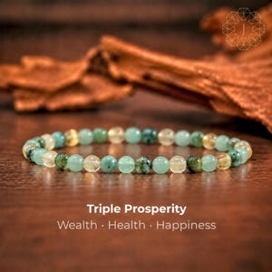 May include: A beaded bracelet featuring alternating round polished green and translucent yellow stones. The text Triple Prosperity Wealth Health Happiness is printed below the bracelet in white sans-serif font.