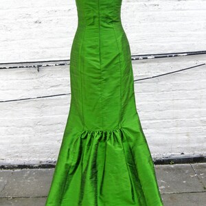 May include: A long, green, sleeveless dress with a fitted bodice and a flowing skirt. The dress has a back zipper closure and a slight ruffle at the hem.