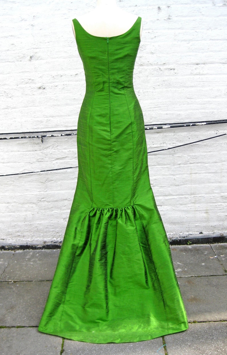 May include: A long, green, sleeveless dress with a fitted bodice and a flowing skirt. The dress has a back zipper closure and a slight ruffle at the hem.