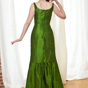 May include: A long green dress with a fitted bodice and a flowing skirt. The dress has a button closure down the back.