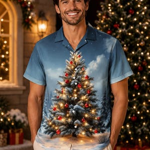 May include: A short-sleeved button-down shirt featuring a blue winter sky background with a large, central Christmas tree graphic decorated with glowing lights and red ornaments, extending across the front panels and collar.