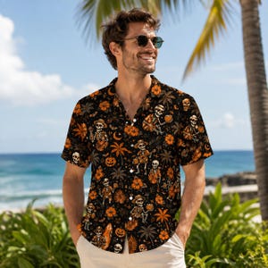 May include: A black short-sleeved button-down shirt featuring an all-over print of skeletons wearing hats, orange pumpkins, tropical palm trees, and orange hibiscus flowers. The shirt has a classic collar and a front button fastening.