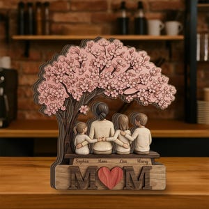 May include: A wooden family tree sculpture featuring a mother and three children under a cherry blossom tree. The base reads "MOM" with a heart, and the names "Sophia", "Mom", "Lisa", and "Henry" are inscribed.