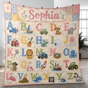 Pode incluir: Uma manta acolchoada com o nome Sophia no topo, seguida por uma grade com as letras do alfabeto de A a Z. Cada letra é acompanhada por uma ilustração colorida, como um avião, barco, carro, cão, elefante, carro de bombeiros, guitarra, helicóptero, iglu, alforreca, papagaio, leão, camião, ninho, polvo, urso pirata, gata rainha, foguetão, barco a vapor, trator, guarda-chuva, vulcão, baleia, raio-x, ioiô e zebra.