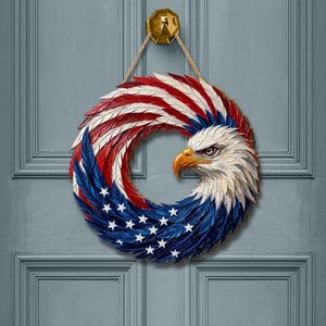 May include: A circular wall hanging featuring a sculpted bald eagle head with a yellow beak, integrated into a wreath design. The feathers are painted in red, white, and blue, with white stars on the blue section, mimicking the American flag.
