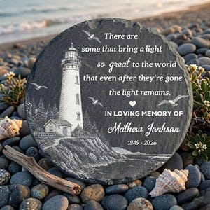 Peut inclure: Une pierre tombale grise et ronde avec une illustration de phare et le texte "There are some that bring a light so great to the world...In Loving Memory of Mathew Jonhson 1949-2026." La pierre est entourée de galets et de coquillages.