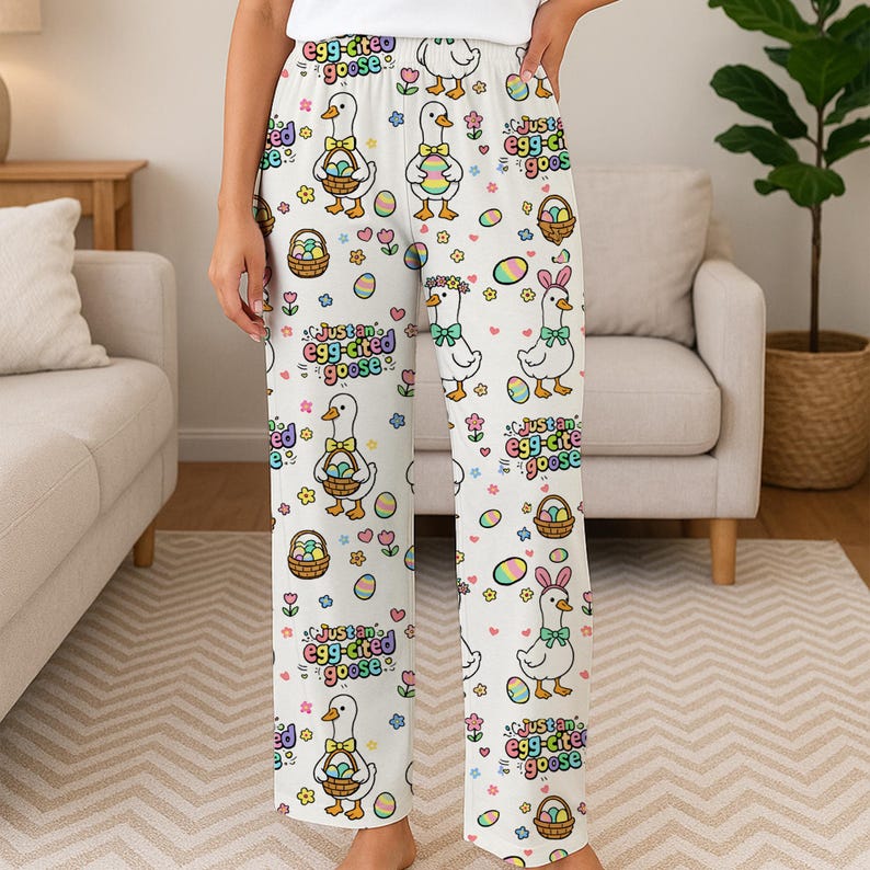 Puede incluir: Pantalones de pijama blancos con un estampado repetido de gansos de dibujos animados con cestas de Pascua, huevos y flores. El texto "Just an egg-cited goose" tambi&eacute;n est&aacute; impreso. Los pantalones son de un material suave y c&oacute;modo.