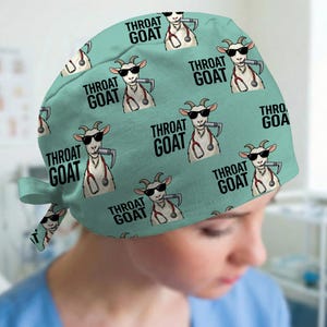 May include: A light green scrub cap featuring a repeating pattern of a white goat wearing black sunglasses and a red stethoscope around its neck, holding a laryngoscope in its mouth, with the black text THROAT GOAT printed next to each goat.