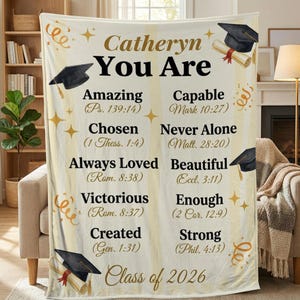 May include: A cream-colored graduation blanket with the text "Catheryn You Are" and inspirational words like "Amazing" and "Chosen." Features graduation caps, scrolls, and the text "Class of 2026."