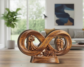 May include: A wooden infinity-shaped ornament featuring a couple kissing on the left and a couple embracing on the right. It is engraved with the names James and Sophia, the text From Our First Kiss Till Our Last Breath, and 50th Wedding Anniversary 1976-2026.
