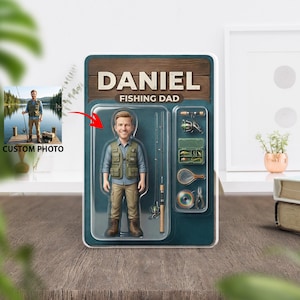 May include: A personalized "Fishing Dad" action figure in a retro-style package. The package features the name "DANIEL" above the text "FISHING DAD". The figure is wearing a fishing vest and holding a fishing rod. Additional fishing gear is displayed on the package.