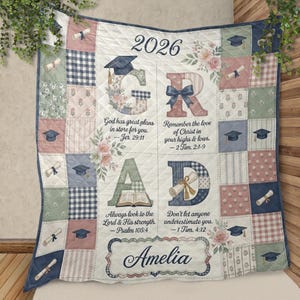 Può includere: Una coperta trapuntata con design patchwork in tonalità tenui di blu, verde e rosa. La coperta mostra il testo 2026 GRAD, versetti religiosi, tochi di laurea, diplomi, accenti floreali e il nome Amelia in un carattere corsivo elegante.