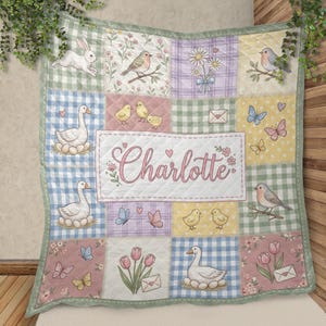 May include: A quilted blanket featuring a patchwork design with pastel colors, gingham patterns, and illustrations of rabbits, birds, chicks, geese, butterflies, and tulips. The center panel displays the name Charlotte in pink cursive script.