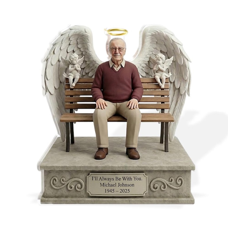May include: A commemorative figurine featuring an older man with glasses wearing a maroon jumper and tan trousers, seated on a wooden bench. Large white angel wings extend behind him with a gold halo above his head and two small cherubs on the bench. The base displays the text: I'll Always Be With You. Michael Johnson 1945-2025.