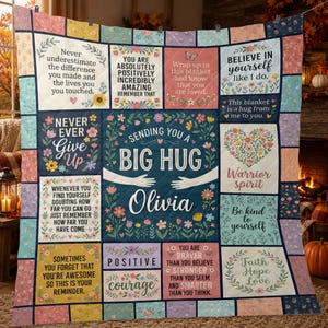 May include: A quilted throw blanket featuring a patchwork design of floral patterns and inspirational text blocks. The center panel displays the text "SENDING YOU A BIG HUG" and "Olivia" with an illustration of arms embracing.