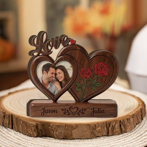 Peut inclure: Un cadre photo double cœur en bois foncé avec le mot Love en haut et un petit cœur rouge. Un cœur contient la photo d'un couple, l'autre présente deux roses rouges. La base est gravée avec les prénoms Jason et Julia.